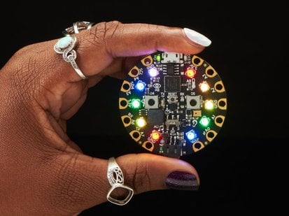 Circuit Playground Express - GH STUDENT EDITION - Hand holding a rainbow-glowing circuit playground