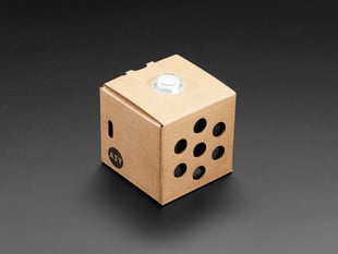 Angled shot of assembled cardboard cube with white button on top.