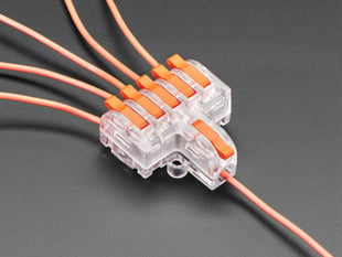 Angled shot of clear 1-to-6 Wiring Block Connector assembled with red wires.