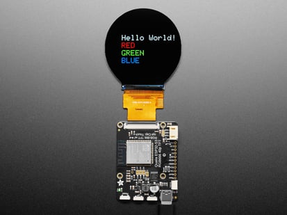 Adafruit Qualia ESP32-S3 for TTL RGB-666 Displays - Overhead shot of TFT driver board connected to a round TFT display, which says, "Hello world!"